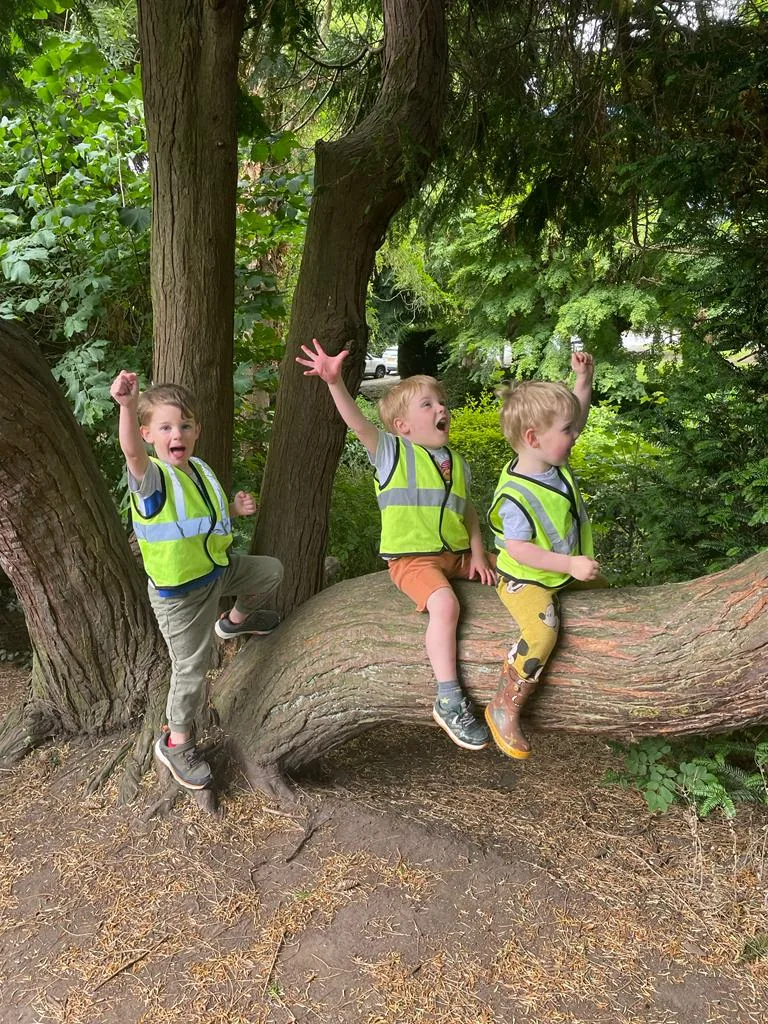 Three Riverside children exploring together by a large tree